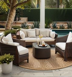 an outdoor living area with wicker furniture and potted plants next to the pool