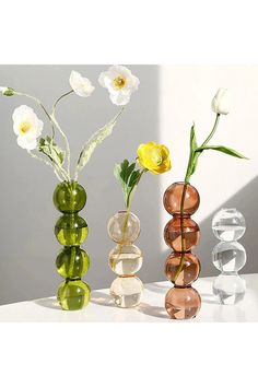 three different colored vases with flowers in them