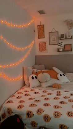 a bedroom decorated for halloween with pumpkins on the bed and lights strung from the wall