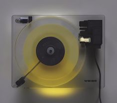 a record player with a yellow light on it's side and an extension cord to the turntable