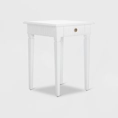 a small white table with one drawer on the top and two legs at the bottom