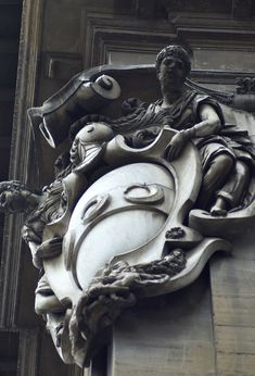 a statue on the side of a building with a clock in it's center