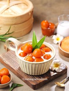 a bowl filled with oranges on top of a wooden cutting board next to other food items