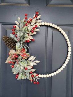 a christmas wreath on the front door with berries, pine cones and mistlet leaves