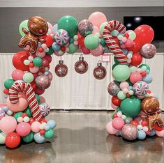 an arch made out of balloons and candy canes is decorated with gingerbread man