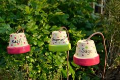 three little bells that are sitting in the grass next to some bushes and trees with writing on them