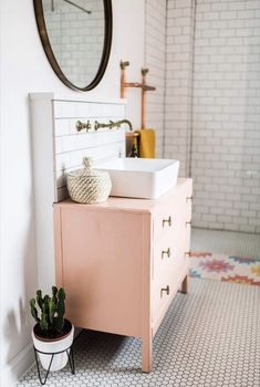 a white sink sitting on top of a wooden cabinet next to a potted plant