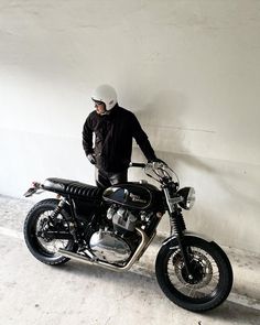 a man standing next to a motorcycle in an empty room with no one on it