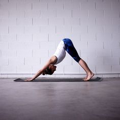 a woman is doing a yoga pose in front of a white brick wall and floor