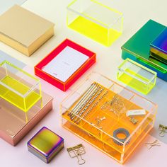 many different colored boxes with various items in them on a white surface, including binders and clips