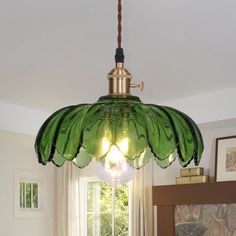 a green glass light hanging from a ceiling in a room with a bed and window