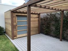 a wooden structure with a door on top of it next to a grass covered yard