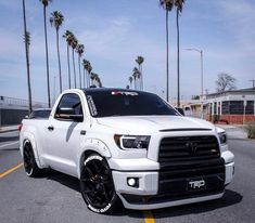 the white truck is parked on the side of the road with palm trees in the background