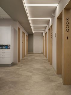 an empty hallway with wooden doors and numbers on the walls, leading to another room