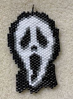 a black and white beaded skull is hanging on the wall in front of a carpet