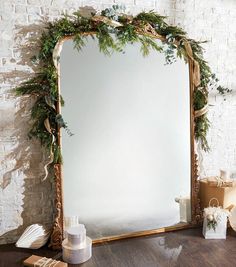 a large mirror sitting on top of a wooden table next to a white brick wall