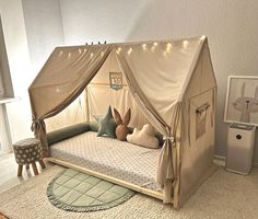 a child's bed with a canopy over it and pillows on the bottom floor