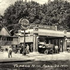 an old black and white photo of people in front of a gas station