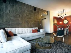 a living room filled with furniture and a glass top table in front of a wall mounted clock