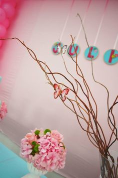 pink flowers in vases and balloons are on the wall next to a blue table