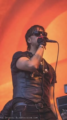 a man with glasses on his face singing into a microphone