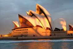 the sydney opera house is lit up at sunset