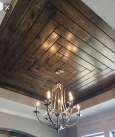 a chandelier hanging from the ceiling in a room with wood paneling on it