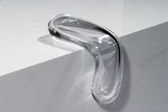 a glass object sitting on top of a white counter next to a wall mounted faucet