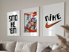 three framed posters hang on the wall above a couch in a living room with white furniture