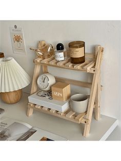 a wooden shelf with candles, books and other items on it next to a lamp