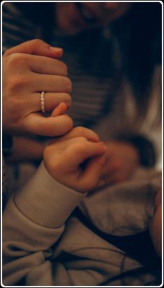 a woman holding the hand of a child who is wearing a ring on her finger