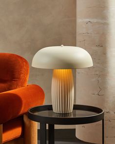 a table lamp sitting on top of a black table next to an orange couch and chair