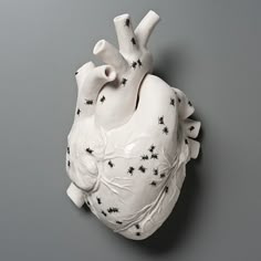 a white ceramic heart with small black stars on it's sides and the top part of its body