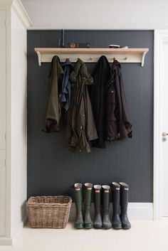 a coat rack with several coats hanging on it and four pairs of rubber boots in the foreground