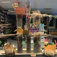 some kind of tree with birds on it in front of a bookshelf filled with books