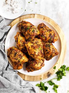 chicken wings on a white plate with parsley and seasoning next to the bowl