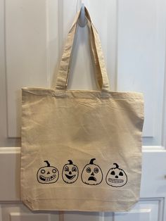 a canvas bag with three faces drawn on it hanging from the front door tote