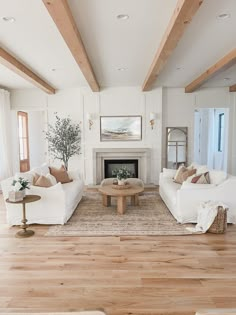 a living room filled with white couches and a fire place next to a fireplace