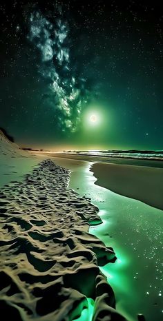 the night sky is lit up with green lights and stars above sand dunes at the beach