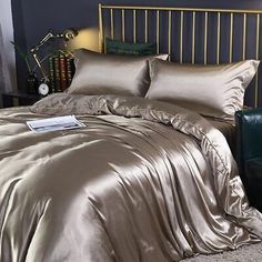 there is a bed with gold sheets and pillows on top of it, next to a green chair