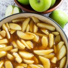 an apple pie with apples in the background and two bowls full of apples next to it