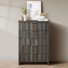 a wooden dresser with drawers and vases on top of it in front of a wall