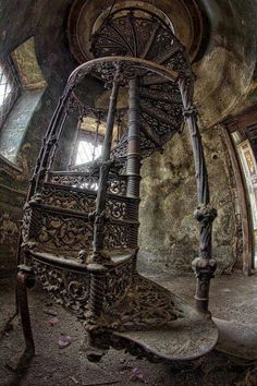 an old spiral staircase in the middle of a room