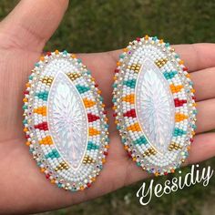 a hand holding two colorful beaded earrings