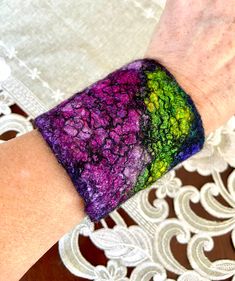 a woman's hand with a colorful bracelet on her left wrist and white lace doily on the table