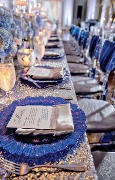 the table is set with silver and blue place settings