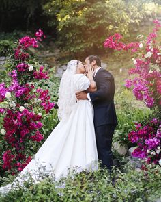 a bride and groom kissing in front of flowers