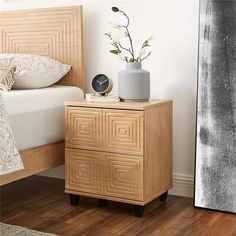 a nightstand with a clock and flowers on it