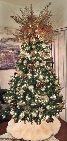 a decorated christmas tree in a living room with white lights and gold ornaments on it