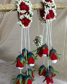 some red and white flowers are hanging from a metal rod with beads on the ends